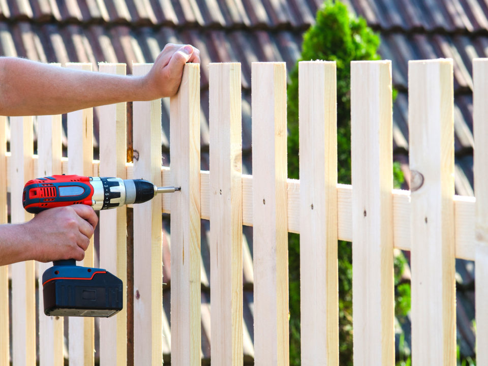 building a wooden fence with a drill and screw. Close up of his